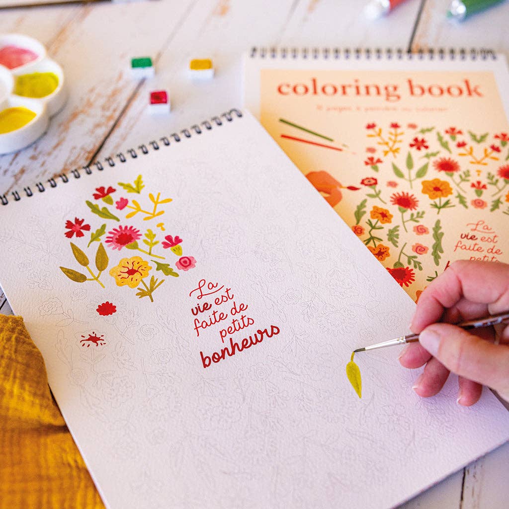 Carnet de coloriage Maison Joliette posé sur une table avec tasse de thé et crayons. Moment créatif et relaxant.