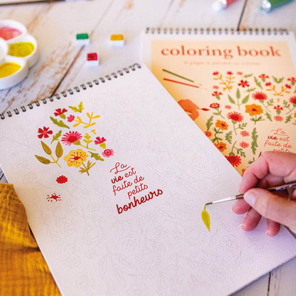 Carnet de coloriage Maison Joliette posé sur une table avec tasse de thé et crayons. Moment créatif et relaxant.