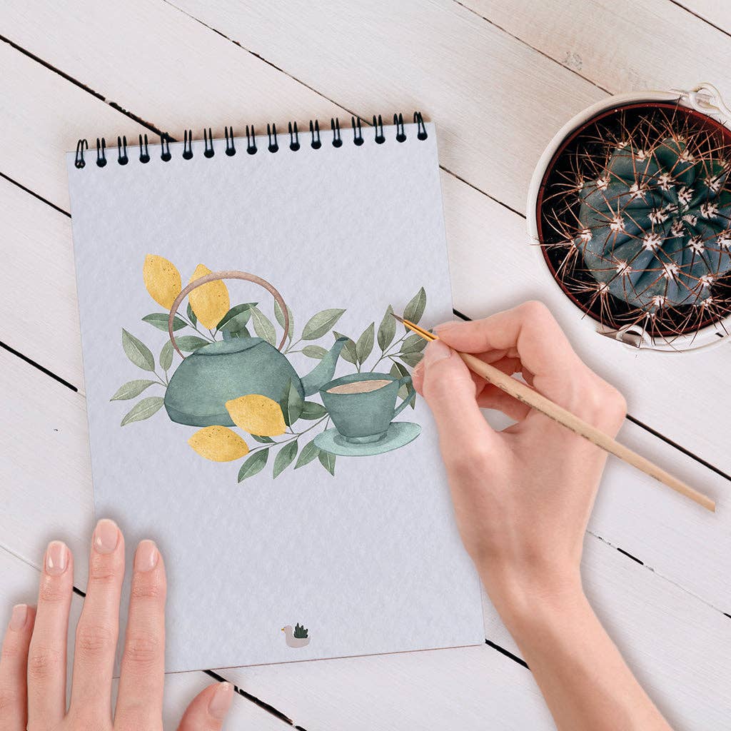 Artiste peignant une fleur à l’aquarelle dans le carnet Cosy Maison Joliette. Papier épais absorbant.