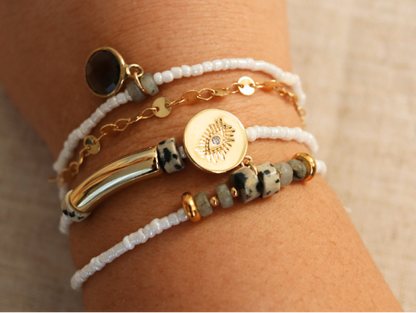 Bracelet multirang blanc réalisé avec perles et pendentifs dorés