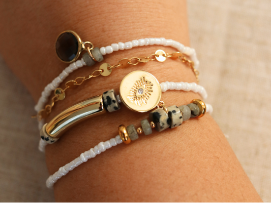 Bracelet multirang blanc réalisé avec perles et pendentifs dorés
