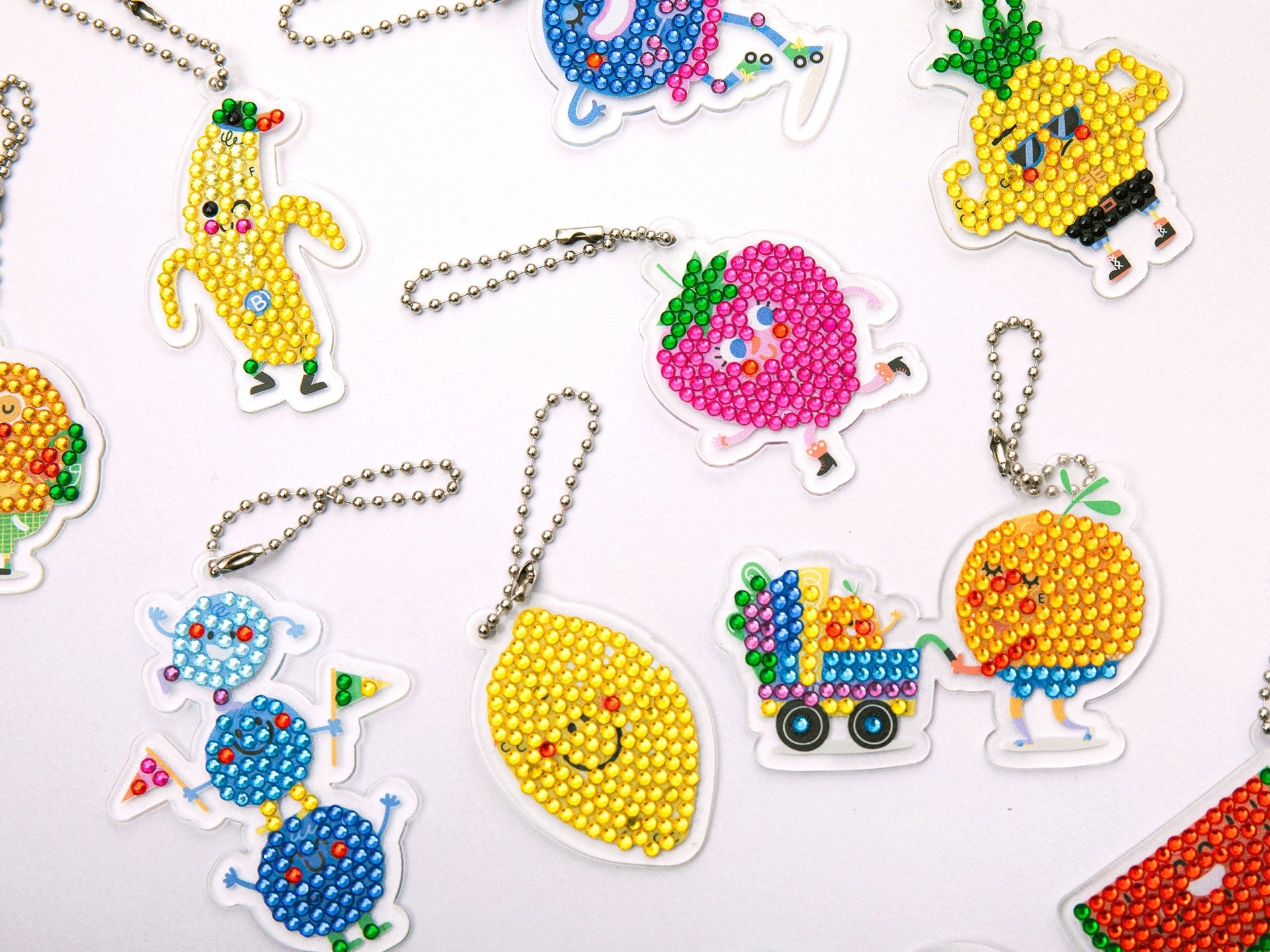 Détail des strass colorés en cours de pose sur un porte-clés fruit.