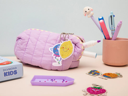 Enfant utilisant le stylet Diamond Painting pour décorer un porte-clés.