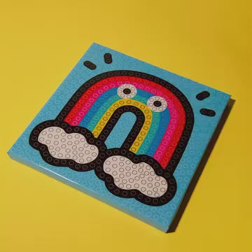 Enfant collant des pompons sur le tableau Arc-en-ciel OMY, activité motricité fine